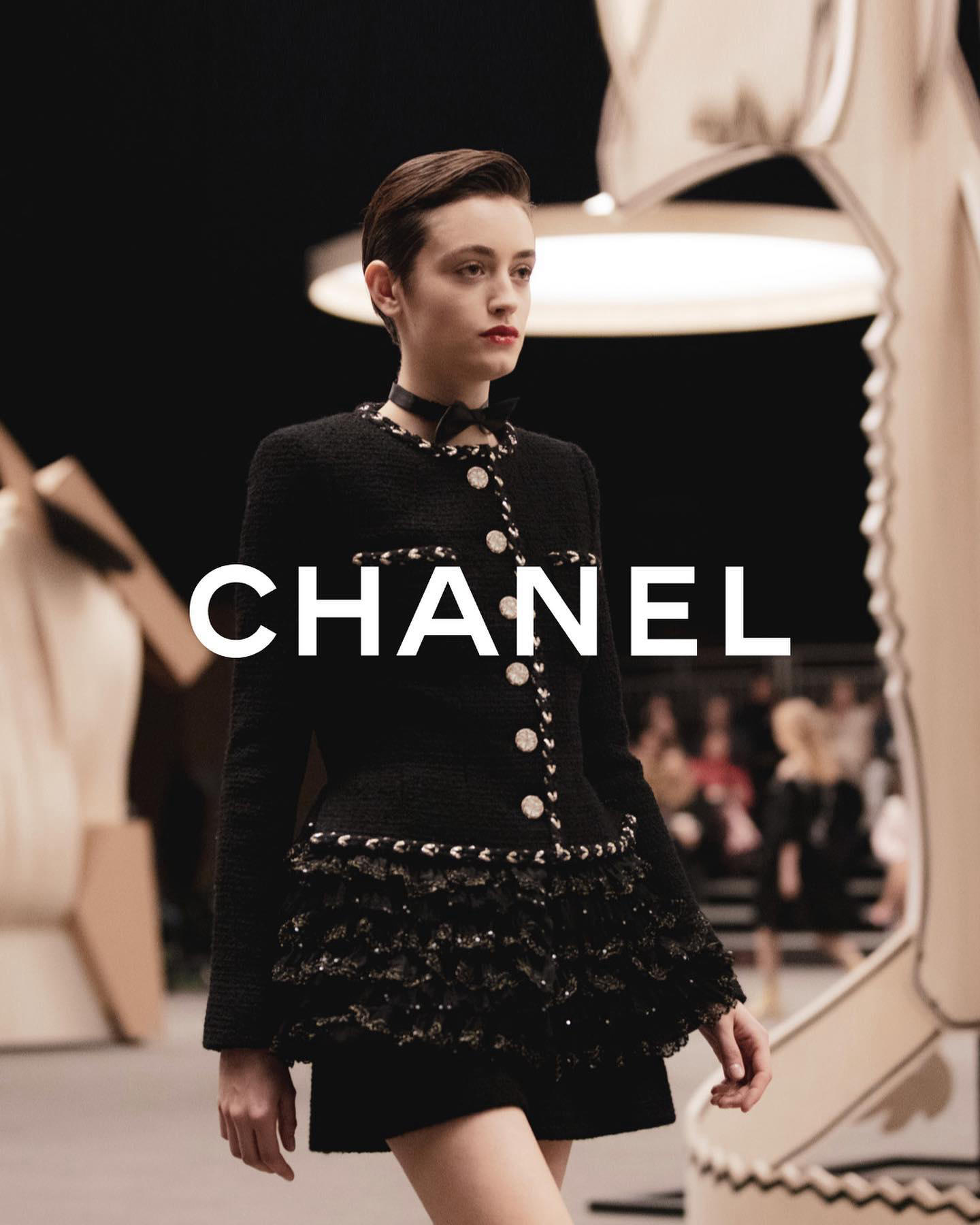 image  1 Glinting with gold, a black CHANEL tweed shorts suit features a construction unique to the world of